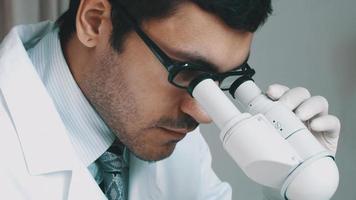 jonge wetenschapper die door de microscoop kijkt
