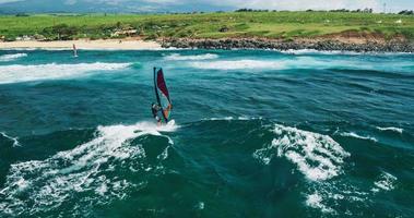vista aérea do windsurfista deslizando pelo oceano azul