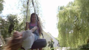 Two Girls Playing On Tire Swing In Garden video