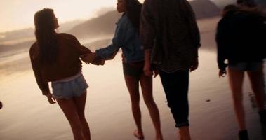 tiener vrienden genieten van een wandeling op het strand bij zonsondergang video