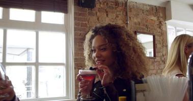 clientes disfrutando de bebidas en el ajetreado bar de cócteles rodado en r3d video