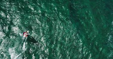 vista aérea do windsurfista deslizando pelo oceano azul