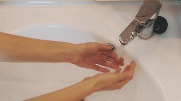 garota torneira aberta da pia no banheiro. água. lavar as mãos. manhã. higiene