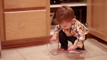 liten pojke som staplar plast på köksgolvet