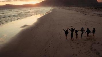 giovani amici adulti che godono di una passeggiata in spiaggia sul tramonto