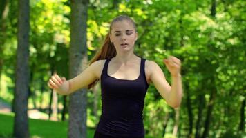 donna facendo esercizi di fitness nel parco verde in primavera. corridore femminile warm up video