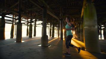 vrouw uit te werken op het strand bij zonsondergang. fitness actieve levensstijl. rennen op het zand video