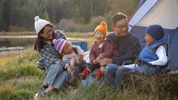 Asian family on a camping trip relaxing outside their tent