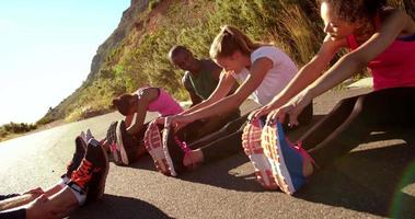 gruppo multietnico di atleti che fanno esercizi di allungamento del tendine del ginocchio all'esterno video