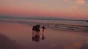 Amigos adolescentes disfrutando de un paseo por la playa al atardecer