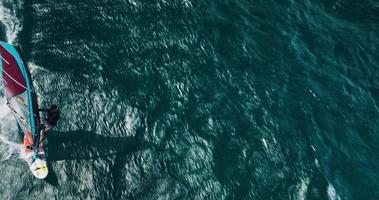 Vue aérienne de la planche à voile glissant sur l'océan bleu