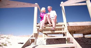 pareja de jubilados sentados juntos en la playa