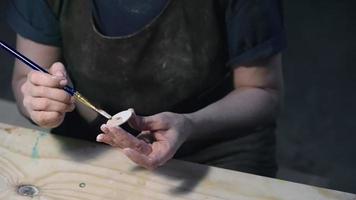 Artesana pintando rueda de juguete de madera