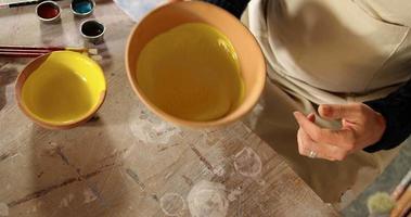 Potier mâle mélange aquarelle dans un bol à l'atelier de poterie