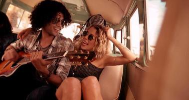 Mujer caucásica hipster sonríe al hombre de raza mixta tocando la guitarra video