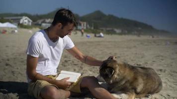 man hangt met zijn hond op het strand