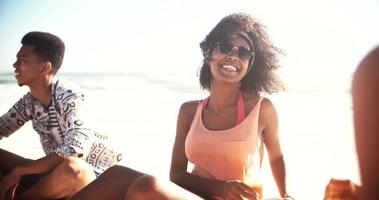 chica afro relajante en la playa con amigos