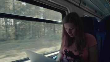 Schwangerschaftsfrau, die mit Laptop in einem Zug arbeitet