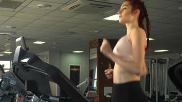 attraktiver kaukasischer junger Teenager, der auf dem Laufband in der Sporthalle läuft video