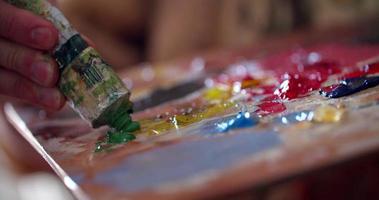 Pinturas multicolores vibrantes en una paleta mezclada con cuchillo video