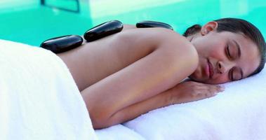 Peaceful brunette getting hot stone massage poolside video