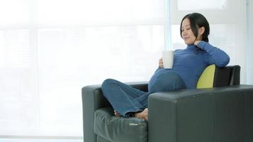 mujer embarazada asiática emplazamiento en un sofá video