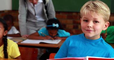 petit garçon souriant à la caméra pendant la classe