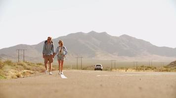 pareja de vacaciones haciendo autostop a lo largo de la carretera rodada en r3d