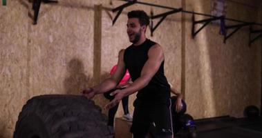 homem praticando ginástica esporte cara jogando pneu grande treino de ginástica, esportista malhando video