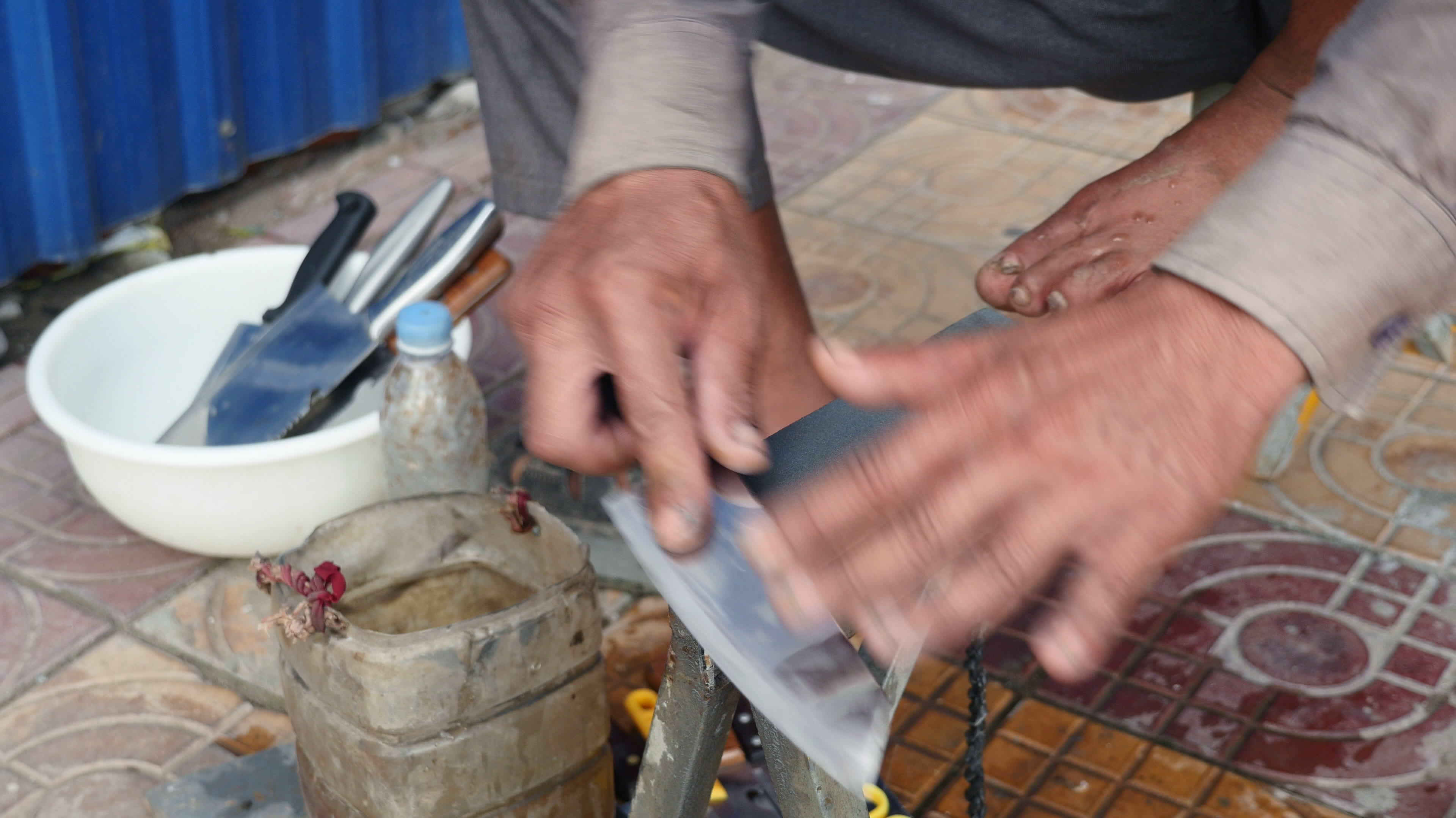 close up on a knife sharpener whetting a knife on the sidewalk and