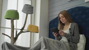 kvinnasammanträde på en säng med en tablett video