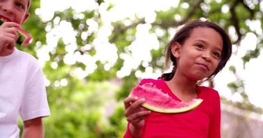 blandad grupp av barn som äter vattenmelon som ler mot kameran video