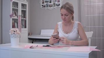 jonge vrouw met behulp van haar telefoon tijdens het uitsnijden van papieren vlinders video