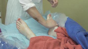 la massaggiatrice fa il massaggio del piede destro a una donna adulta nel salone. cura della pelle. terapia video