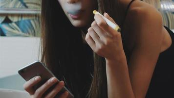 Ritratto di giovane ragazza sedersi sul water con il telefono e il fumo di sigaretta elettronica video