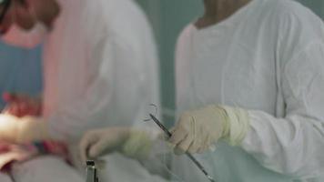 enfermeira preparar agulha e linha na sala de cirurgia. cesáriana. cirurgiões