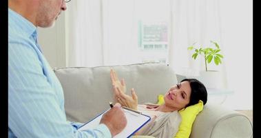 Mujer embarazada acostada en el sofá hablando con el terapeuta video