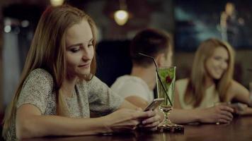 mujer enviando mensajes de texto en el bar
