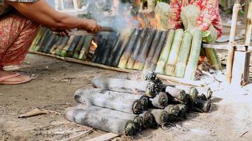 kvinna som vrider bambukakor som lagar mat i brand