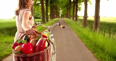 Frau im Park mit Fahrrad und Korb des Gemüses
