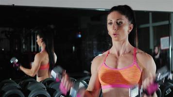 atletisk kvinna tränar muskler i händerna. kvinnlig bodybuilding video