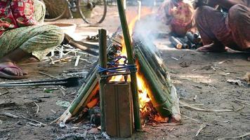 kvinna som vrider bambukakor som lagar mat i brand