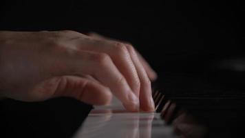 poca profundidad de campo, manos de mujer tocando el teclado del piano, presione la tecla en blanco y negro