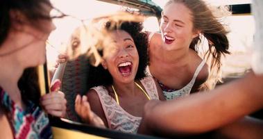 Chica afro riendo con amigos en cámara lenta de viaje por carretera