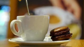 Cup of coffee with brown macaron in an indoor café video