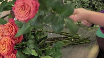 a florist manufactures a bouquet of roses