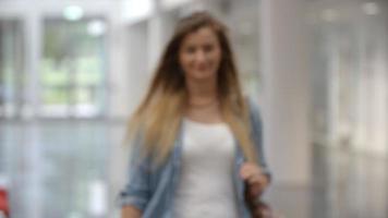 Female university student in a modern lobby walks into focus