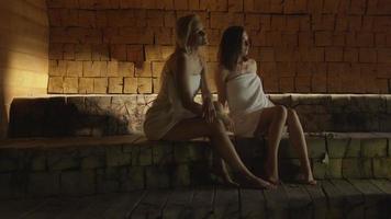 Zwei attraktive Mädchen in Handtüchern entspannen sich in einem Dampfbad im Spa-Wellnesscenter. video