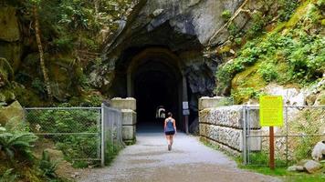 Femme entre dans le tunnel ferroviaire, chemin de gravier, tunnels d'Othello, Hope BC Canada video