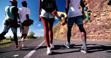 Cropped shot of cool teenage longboarders marchant côte à côte sur une route